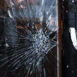 Close-up of a cracked window with a weathered wooden frame and grunge texture.