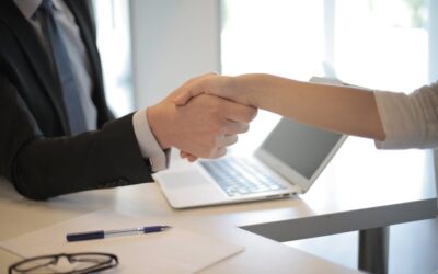 Close-up of a professional handshake over a laptop during a business meeting in an office.