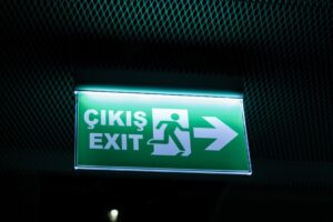 a green exit sign hanging from the side of a wall