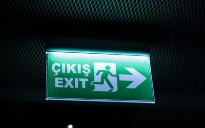 a green exit sign hanging from the side of a wall