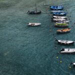 A serene aerial view of various boats anchored in a tranquil harbor with rippling water.