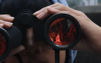 Someone is looking through binoculars, observing something.