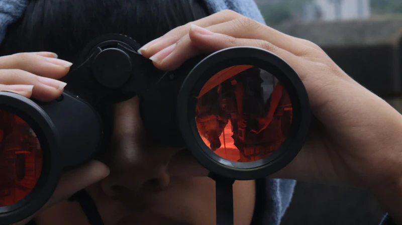 Someone is looking through binoculars, observing something.
