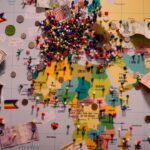 A world map is covered with pins and mementos.