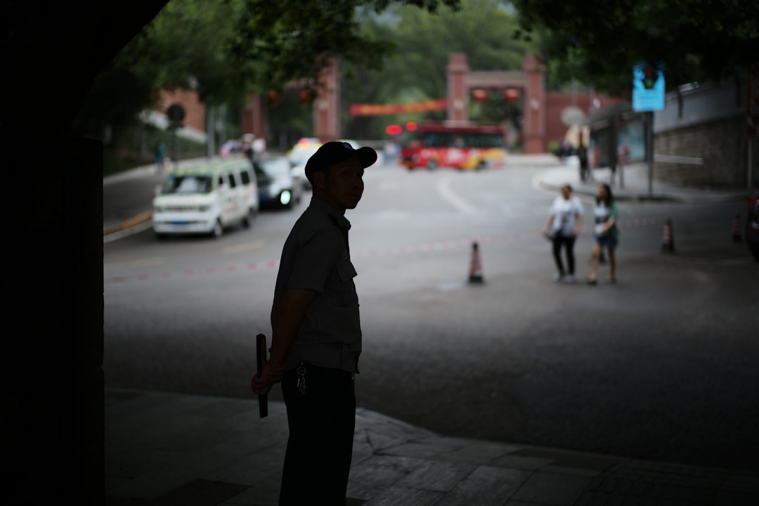 Man in uniform stands by street with traffic.