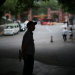 Man in uniform stands by street with traffic.