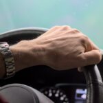 Hand gripping a steering wheel while driving.