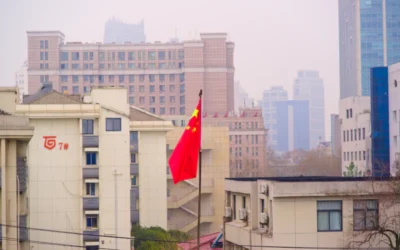 a red and yellow chinese flag in front of a city skyline
