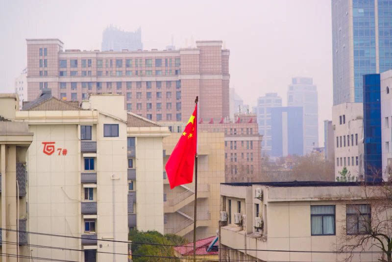 a red and yellow chinese flag in front of a city skyline