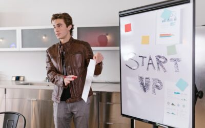 A young entrepreneur gives a presentation on startup strategies indoors with a flip chart.