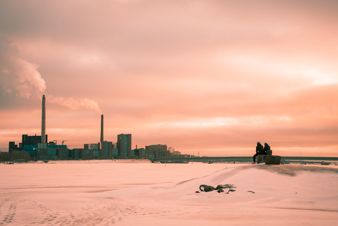 a couple of people sitting on top of a snow covered field