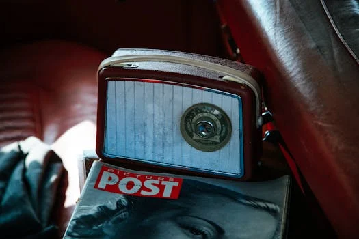 Retro radio on a leather car seat with a Picture Post magazine, evoking vintage nostalgia.