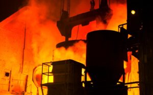 A striking view of molten metal casting in an active steel mill, highlighting intense heat and flames.