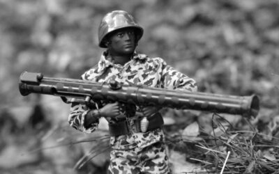 A man in camouflage holding a rifle in a field