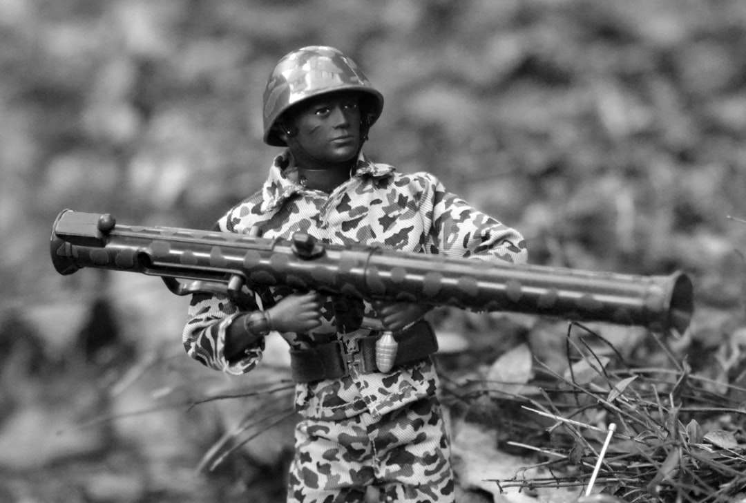 A man in camouflage holding a rifle in a field