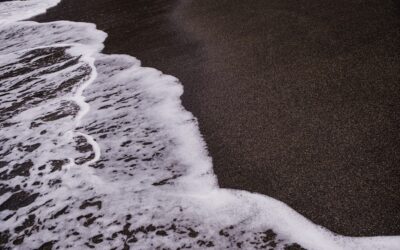 a black sand beach with waves coming in to shore
