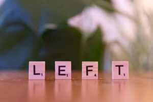 Close-up of wooden Scrabble tiles spelling the word ‘LEFT’ on a blurred background. Close-up of wooden Scrabble tiles spelling the word 'LEFT' on a blurred background.