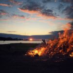 view photography of fire near lake during dawn