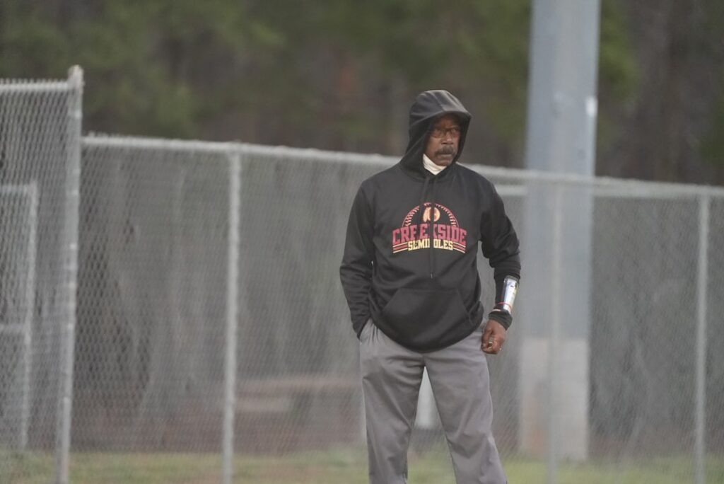 a man standing on a baseball field wearing a hoodie