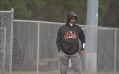 a man standing on a baseball field wearing a hoodie