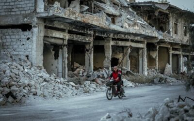 a person riding a bike in front of a destroyed building