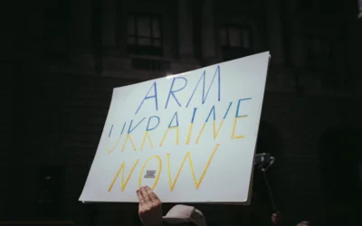 a person holding a sign that says arm ukraine now