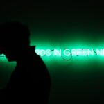 silhouette of man standing near green neon light