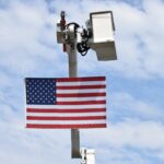 American flag on a pole with security camera.