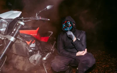 Person in mask and hoodie next to motorcycle