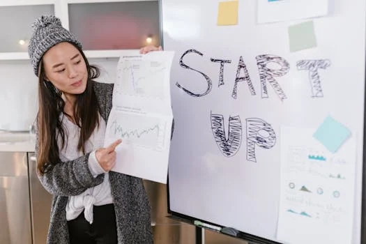 Asian woman presenting business growth charts during a startup pitch indoors.