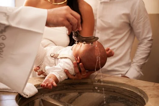 A meaningful baptism ceremony with a baby held by family members in a church setting.