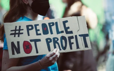 a woman holding a sign that says people not profits
