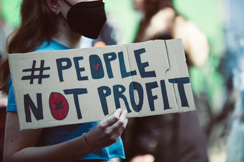 a woman holding a sign that says people not profits