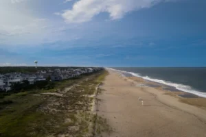 an aerial view of a beach with houses and a hot air balloon in the distance