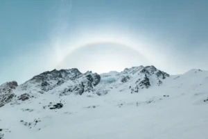 a snow covered mountain with a rainbow in the sky