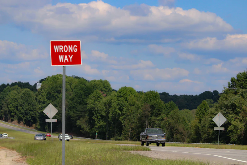 A red wrong way sign sitting on the side of a road