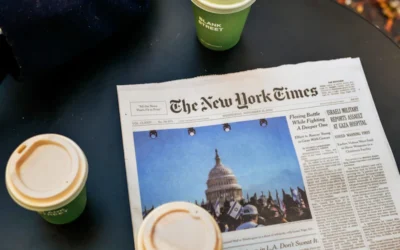 a newspaper sitting on top of a table next to two cups of coffee
