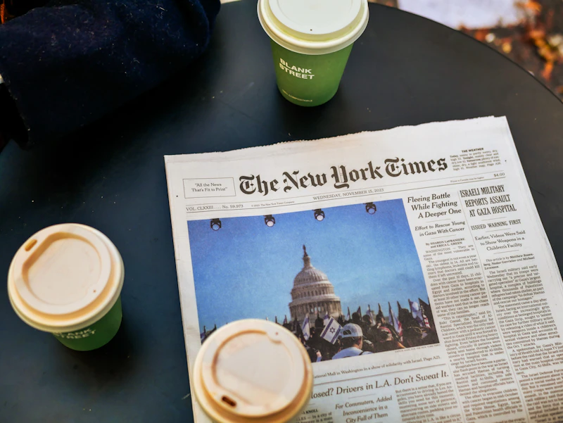a newspaper sitting on top of a table next to two cups of coffee