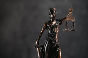 Detailed bronze Lady Justice statue with scales and sword against a dark background, symbolizing law and justice.