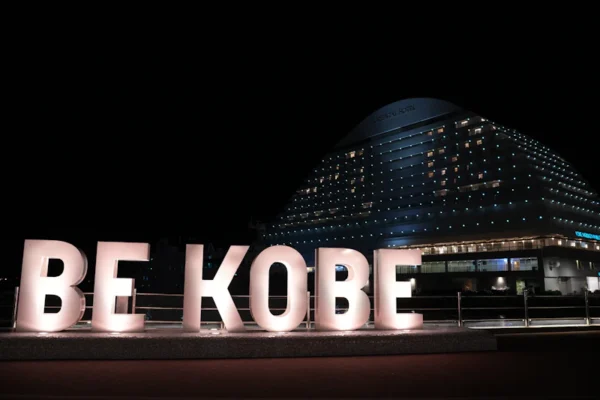 A large sign that says be kobe in front of a building