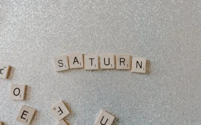 Scrabble tiles forming the word SATURN on a sparkling glitter background, space theme.