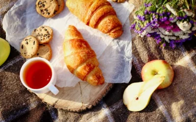 Enjoy a cozy breakfast with croissants, cookies, fruit, and a cup of tea on a rustic table.