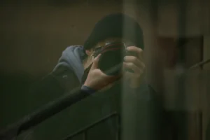 man in gray jacket holding black framed eyeglasses