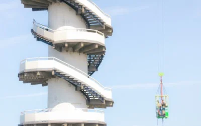 A daring bungy jump beside a striking spiral staircase against a clear blue sky in the Netherlands.