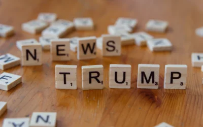 A wooden table topped with scrabble letters spelling news, trump