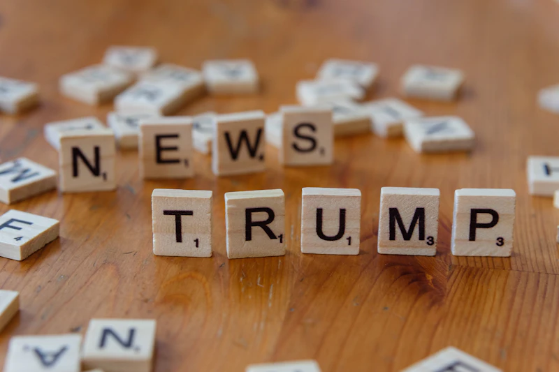 A wooden table topped with scrabble letters spelling news, trump