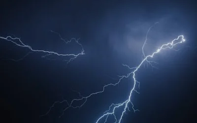 Captivating image of bright lightning bolts striking through dark skies during a nighttime storm.