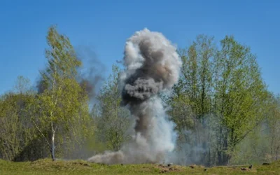 A powerful explosion creates a huge cloud of smoke against a backdrop of green trees, illustrating nature vs. destruction.
