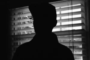 a man standing in front of a window in the dark