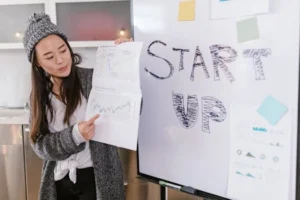 Asian woman presenting business growth charts during a startup pitch indoors.